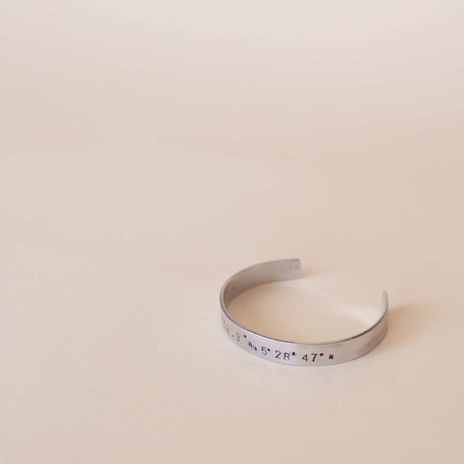 Silver bracelet with engraved text on a beige background